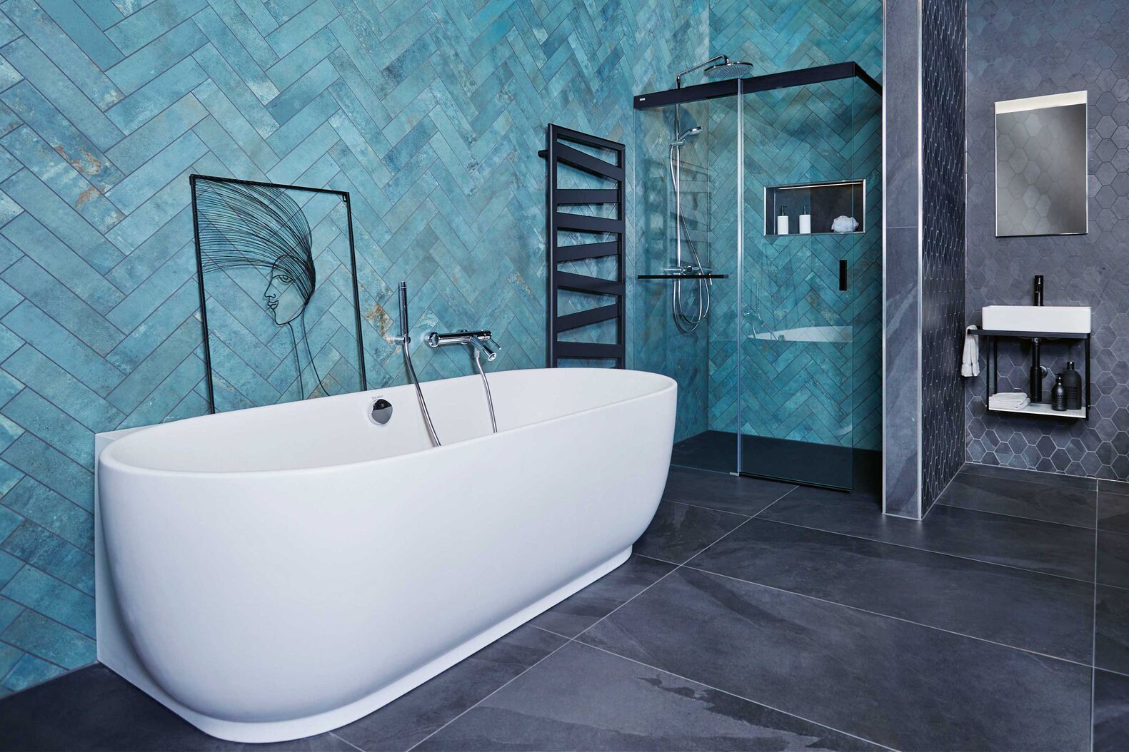 Die edlen Wandplatten in Smaragdgrün laden zum Verweilen unter der Regendusche ein. Der Übergang von schwarzen grossformatigen Keramikplatten zum kleineren Polygonformat schenkt dem Raum zusätzliche Tiefe. SABAG Biel/Bienne, www.sabag.ch