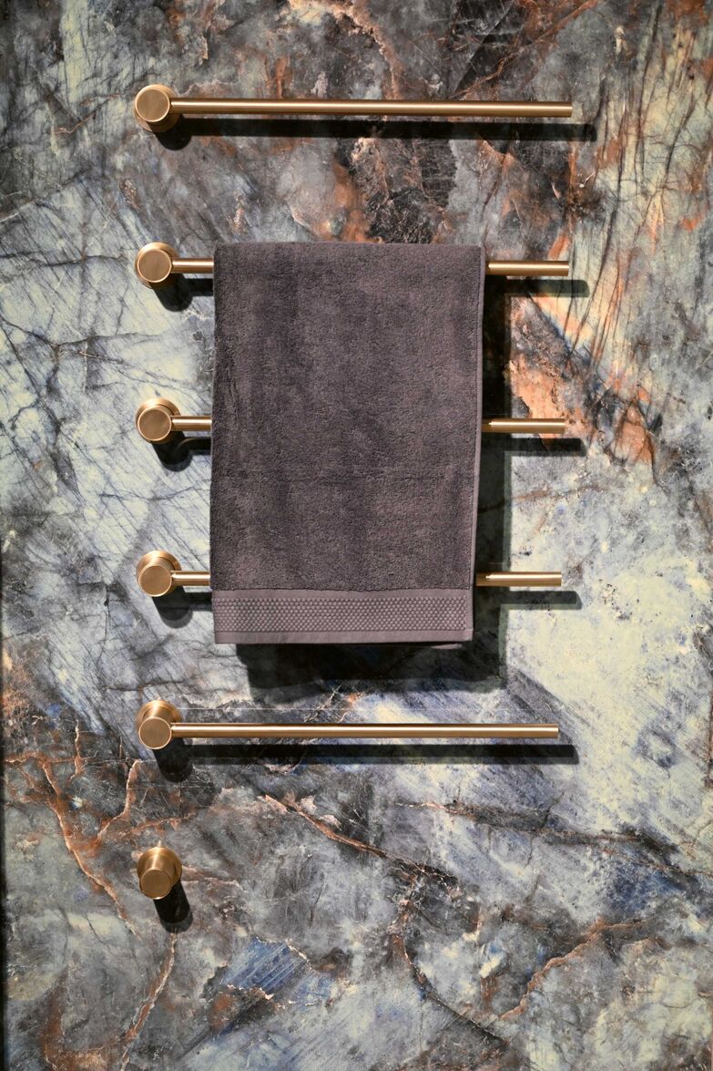 Die Fliesen aus Feinsteinzeug harmonieren perfekt mit dem Handtuchwärmer von Vola aus gebürstetem Messing. Hug Baustoffe AG, www.hug-baustoffe.ch