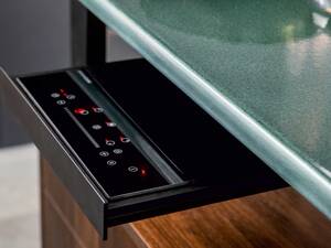 Aussergewöhnlich: Die Arbeitsplatten aus robustem Lavagestein sind zugleich Induktionskochfelder, die schnell aufheizen und auch rasch wieder abkühlen. Die Bedienung erfolgt über ein ausziehbares Tableau. Elbau Küchen AG.