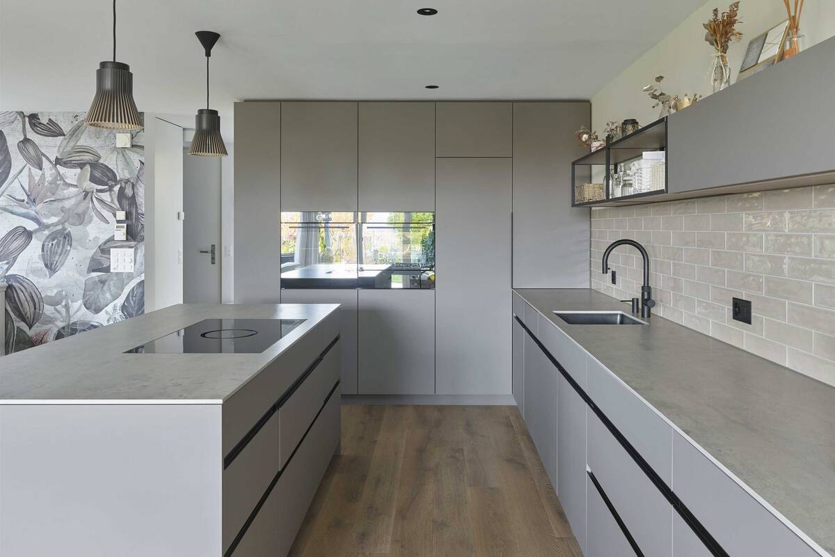 Beim Küchenumbau in Bolligen wurde auf einen schlichten Industrielook mit offenen Metalloberbauten und schwarzen Aluprofilen gesetzt. Der Wasserhahn ist von Quooker. Oesch Innenausbau AG.