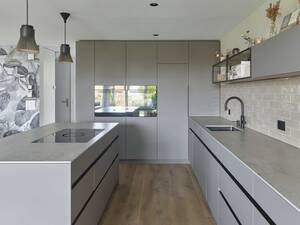 Beim Küchenumbau in Bolligen wurde auf einen schlichten Industrielook mit offenen Metalloberbauten und schwarzen Aluprofilen gesetzt. Der Wasserhahn ist von Quooker. Oesch Innenausbau AG.