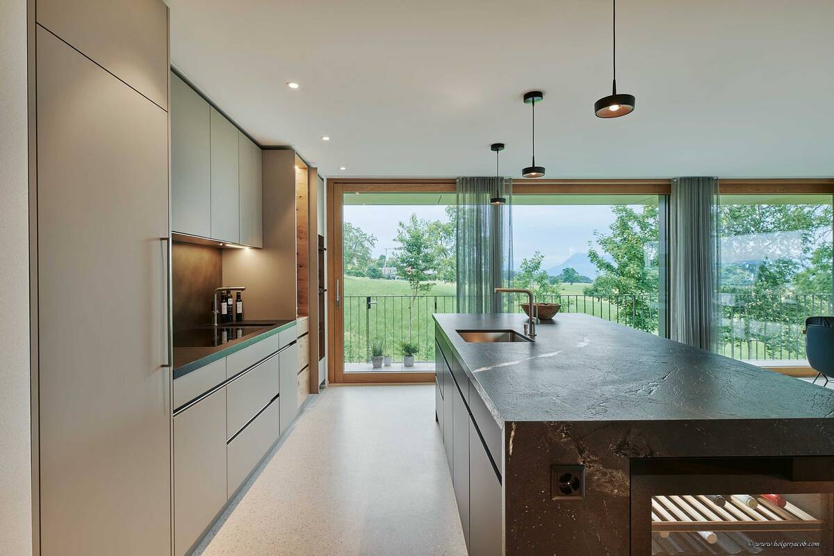 Als verbindendes Element wurde in dieser Küche die Rückwand beim Kochen sowie die Nische der Insel mit Messing ausgearbeitet. Der Negresco Granit wurde so bearbeitet, dass er eine lederne Oberflächenstruktur aufweist. Brunner Küchen AG.