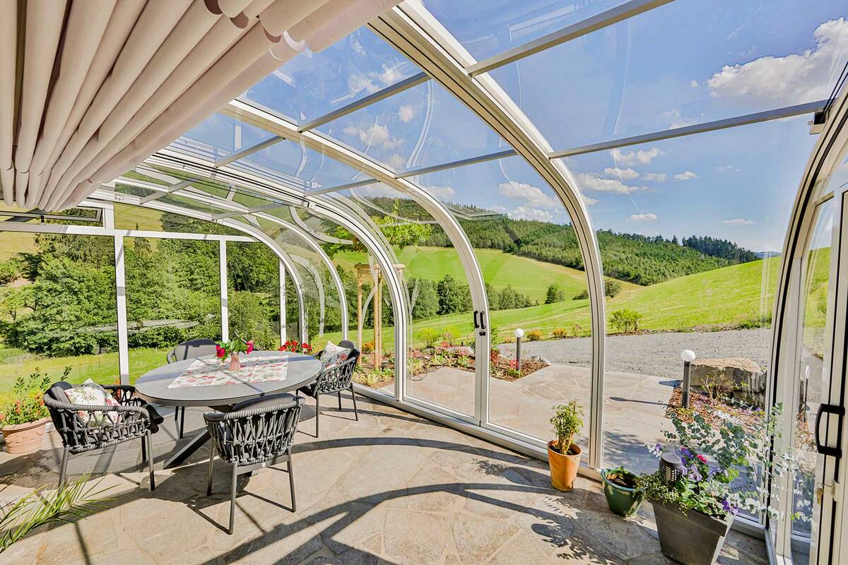 Sonnenstrahlen im Winter: Die gebogene, transparente Dachfläche der Solarveranda «Saphir» bietet einen freien Blick nach draussen. Die Sonnenstrahlen werden gebündelt und verstärkt nach innen geleitet. So wird es im Winter, selbst bei Minusgraden, schnell angenehm warm – ganz ohne Heizung. Wenn es die Aussentemperaturen zulassen, lässt sich die Glasüberdachung weit öffnen. Die Konstruktion ermöglicht es, die Glasüberdachung bei entsprechenden Aussentemperaturen weit zu öffnen und so die Veranda in einen Freisitz zu verwandeln. Vöroka GmbH.