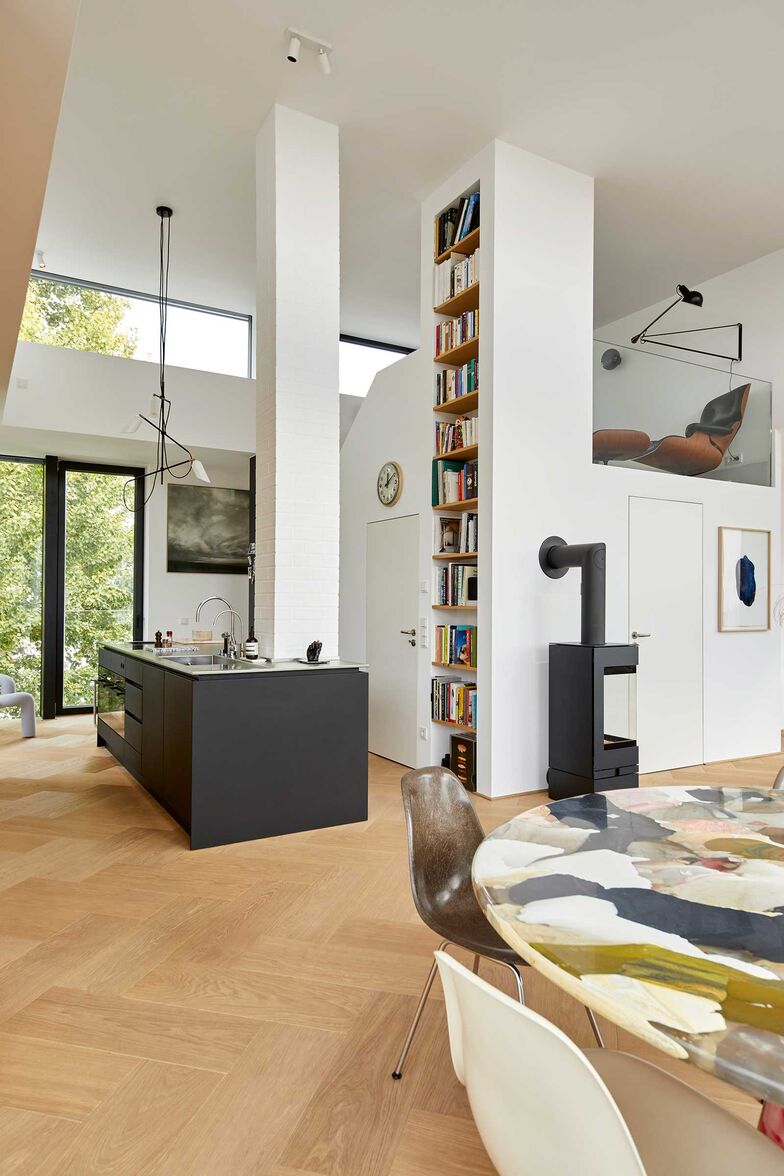 Zwischenebenen schaffen kleine Rückzugsorte, wie hier mit dem ikonischen Eames Lounge Chair von Vitra. Durch die Raumhöhe ergeben sich auch spannende Gestaltungsmöglichkeiten, wie das eingebaute, überhohe Bücherregal.