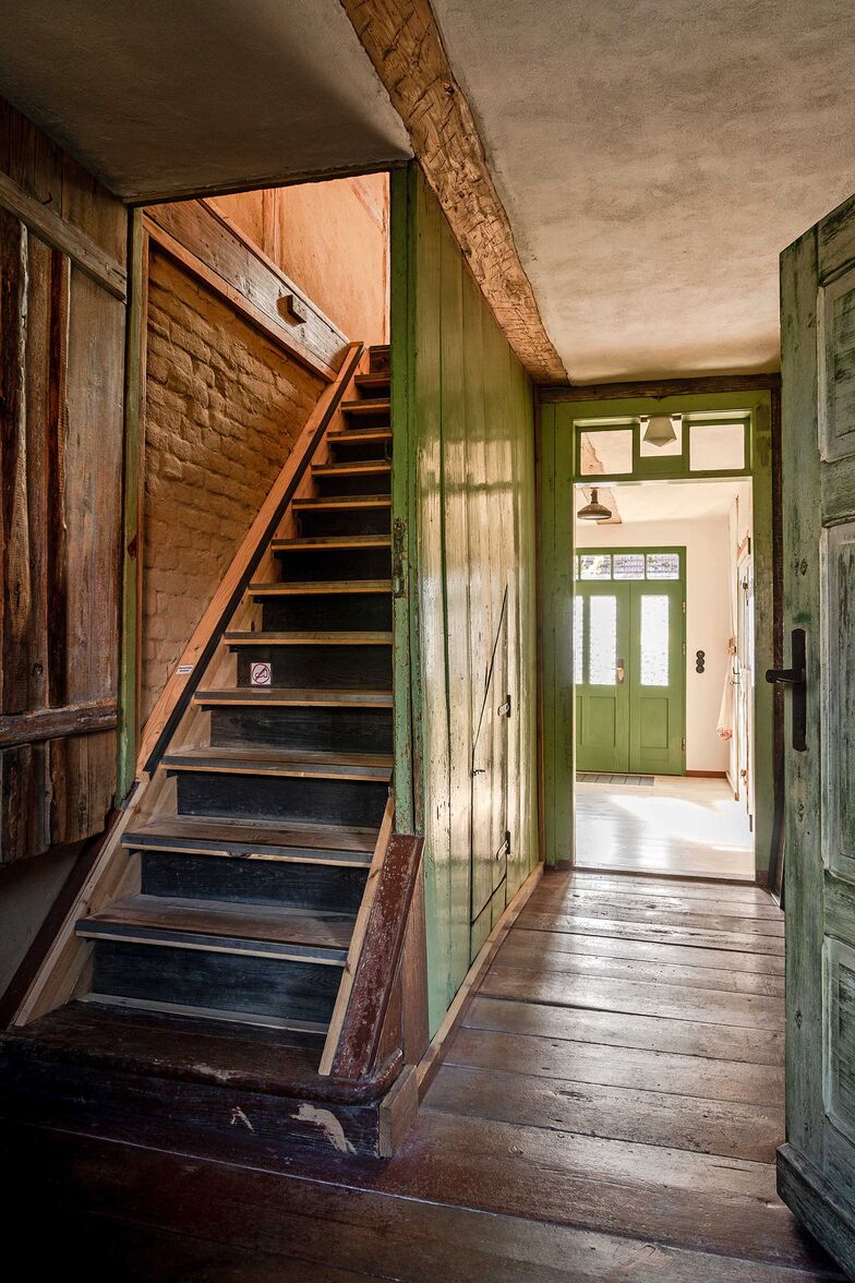 Viele originale Bauteile blieben erhalten und wurden behutsam in die neue Nutzung integriert. Die aufgearbeiteten Türen und Holzböden machen die Geschichte des Hauses sichtbar.