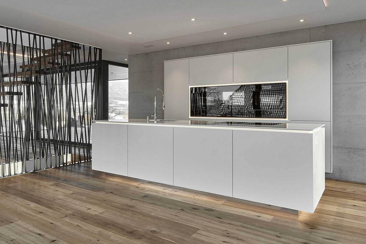 Die grifflosen Fronten unterstreichen den  minimalistischen Stil der Küche. Bei der schwebend  wirkenden Arbeitsplatte handelt es sich um den  Kunststein «Silestone Blanco Zeus». Furrer Küchen AG.