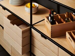Gut verstaut: Die Möbel aus Esche bewahren allerlei Küchenutensilien hübsch auf. Dabei setzt das Regal aus italienischem Schiefer oder Stahlrohr gekonnt Akzente. Brunner Küchen AG.
