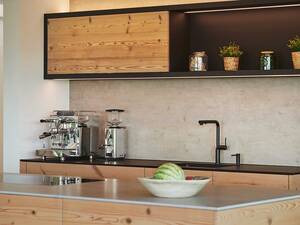 Umgebaut wurde zuerst die Küche, dann die gesamte Liegenschaft. So verhielt es sich auch mit dem Altholz, das als Erstes in Bezug auf die Küche zum Thema wurde und dann auch in weitere Räume kam. Das rustikale Holz wird mit der Beton–optik der Abdeckung und der Rückwand ausbalanciert. Brunner Küchen AG.