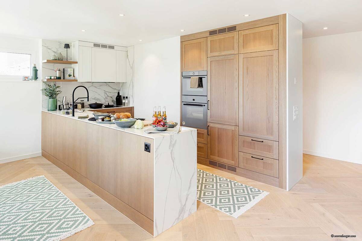 Die charakteristische Maserung des massiven Eichenholzes und die Marmor-Musterung der Keramikflächen sorgen für spannende Kontraste. Herzog Küchen AG.