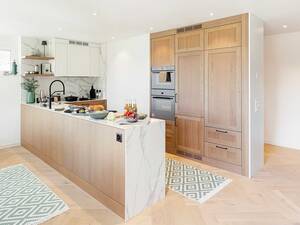 Die charakteristische Maserung des massiven Eichenholzes und die Marmor-Musterung der Keramikflächen sorgen für spannende Kontraste. Herzog Küchen AG.