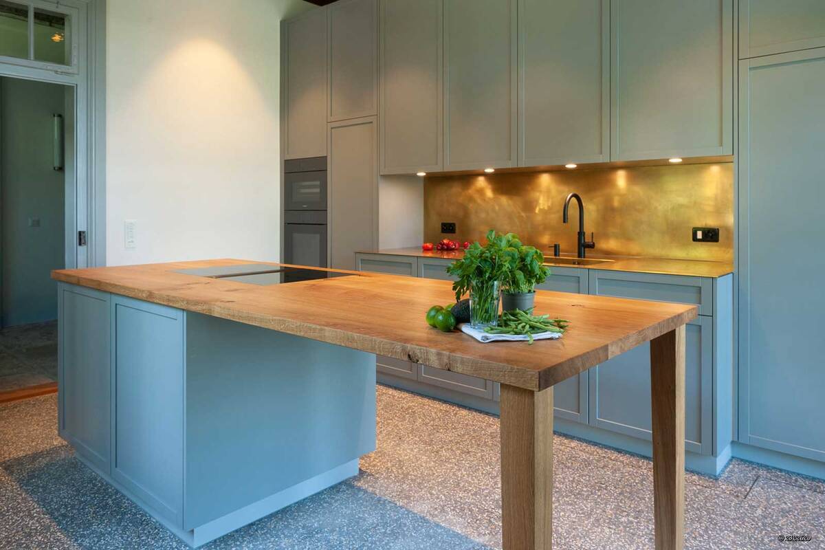 Späti Innenausbau setzt bei dieser individualisierten Küche auf einen ausgewogenen Material- und Farbenmix. Ein Highlight bildet die Arbeitsplatte in «Eiche massiv», die sich über die Kochinsel nahtlos bis hin zum Anbautisch erstreckt. Späti Innenausbau AG.