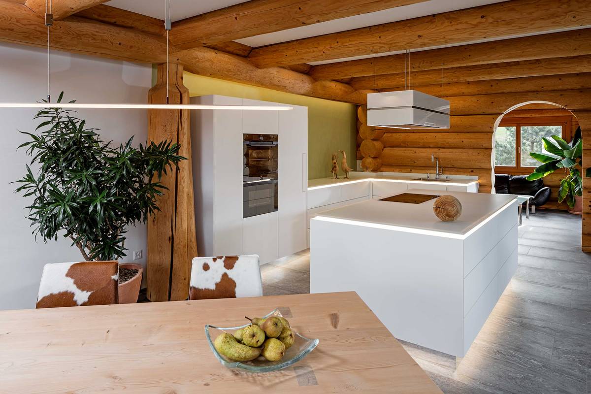 Gradlinige, moderne Küche trifft auf Blockhaus. Die edlen Materialien schmiegen sich fast nahtlos an die massiven Baumstämme der Wände. Furrer Küchen.