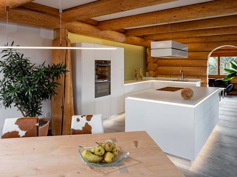 Gradlinige, moderne Küche trifft auf Blockhaus. Die edlen Materialien schmiegen sich fast nahtlos an die massiven Baumstämme der Wände. Furrer Küchen.