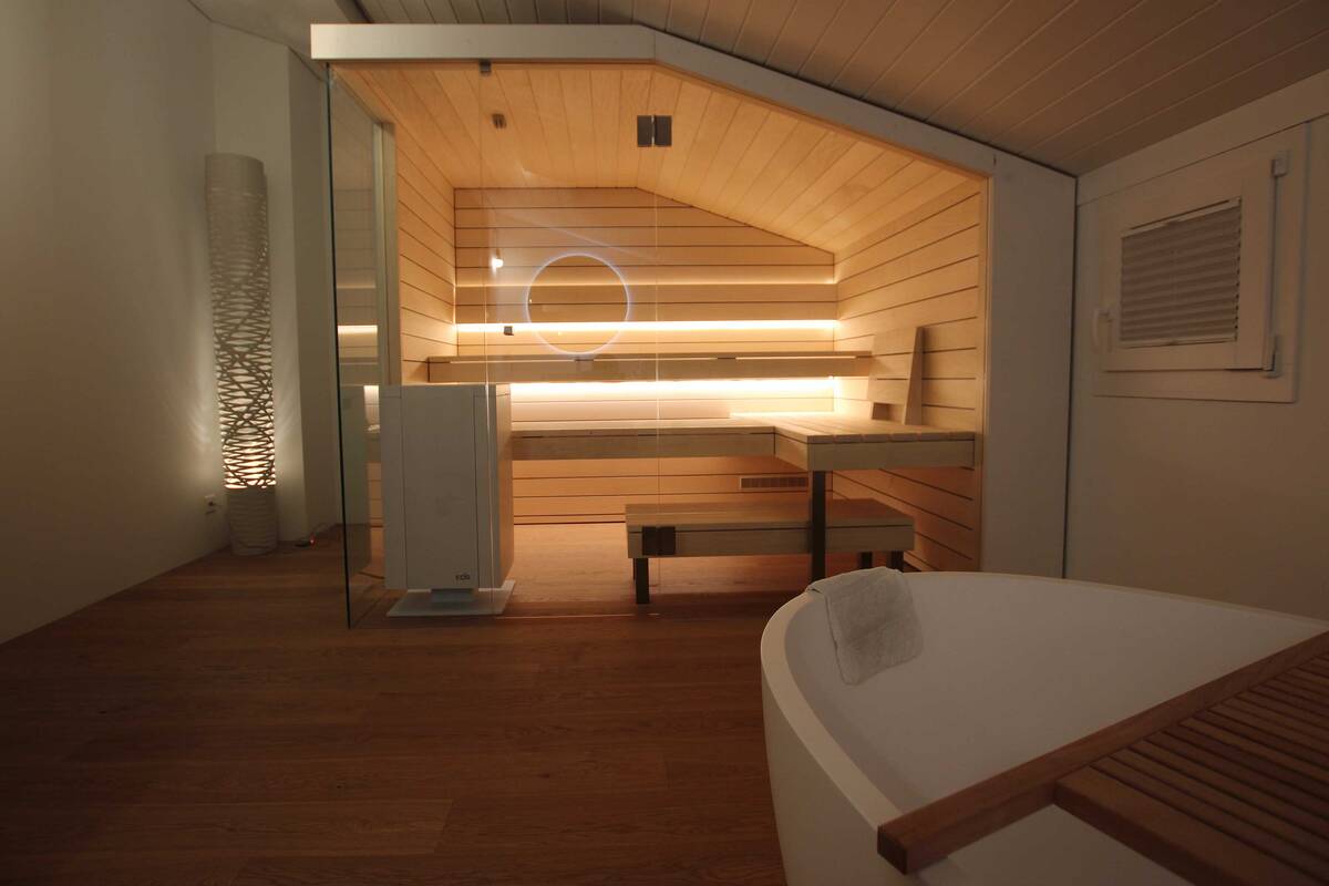 Auch eine Dachschräge erlaubt ein eigenes Wellness-Refugium. Die Sauna aus Espenholz lässt dank der Glasfront den Raum trotzdem grosszügig wirken. Ging Saunabau AG.