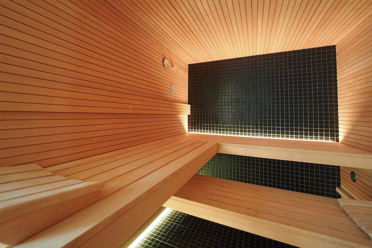 Dunkles Grün und das warme Holz sorgen für eine stimmige Farbgebung der Sauna im Stabprofil. Eingesetzt wurde das robuste Holz der Hemlock-Tanne. Sanatherm.