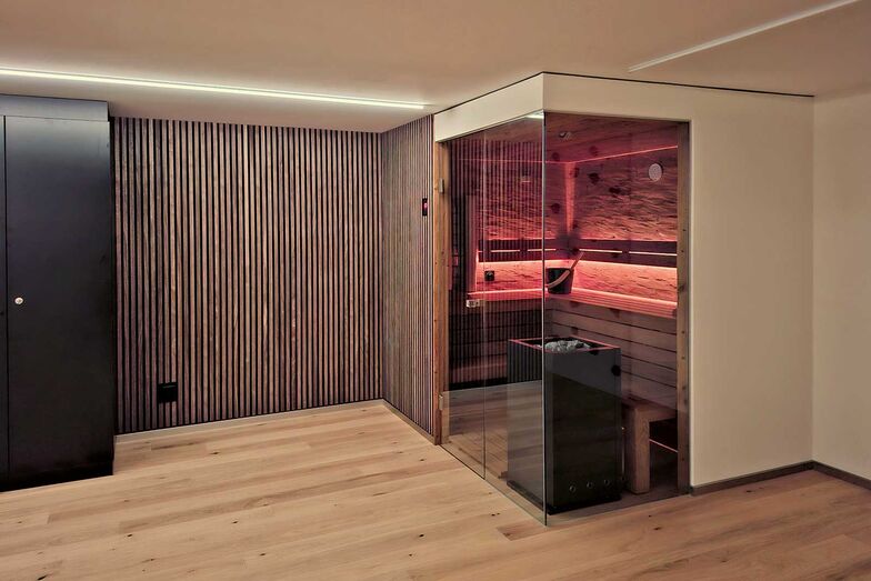 Die Sauna ist in der Ecke des Raumes platziert und bietet Platz für Entspannung.
